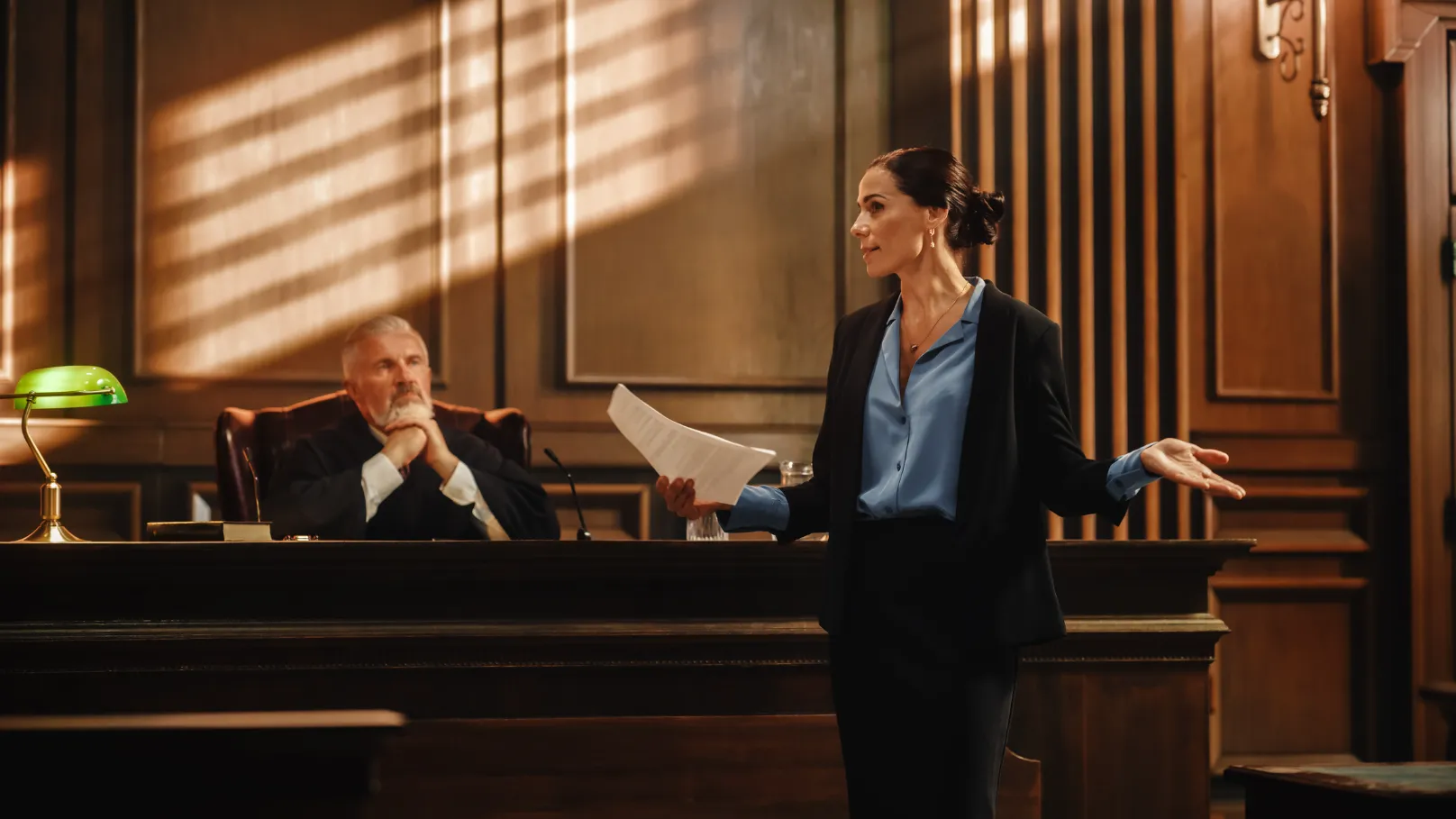 An attorney speaking in front of a judge in a courthouse.