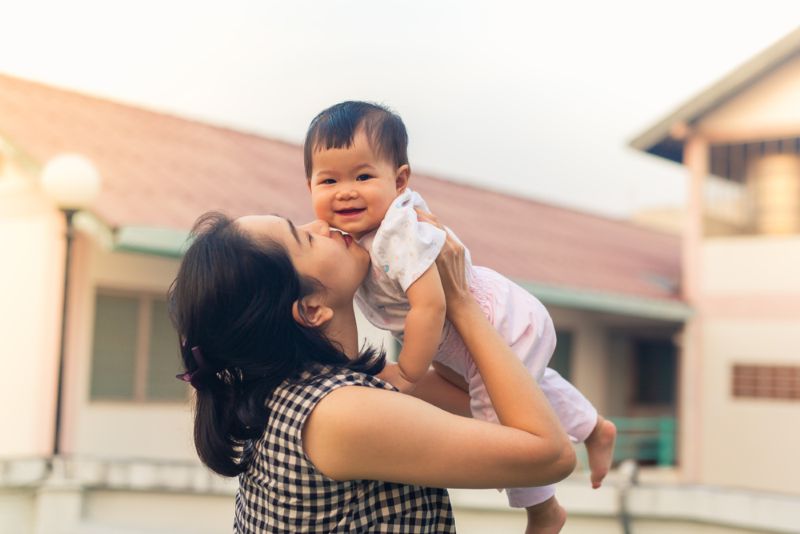 Woman holding her smiling baby outside