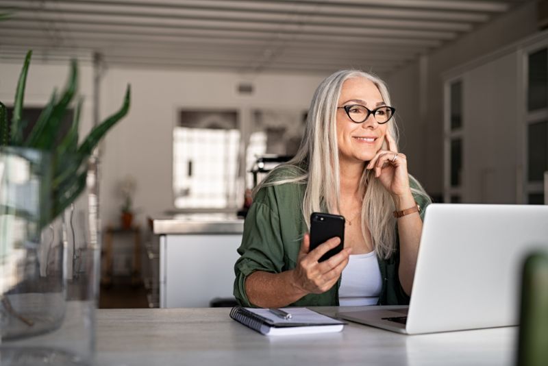Woman using laptop and smiling while on the phone