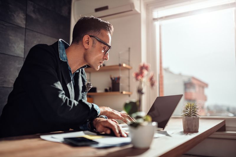 Man scrolling on his laptop from his home kitchen