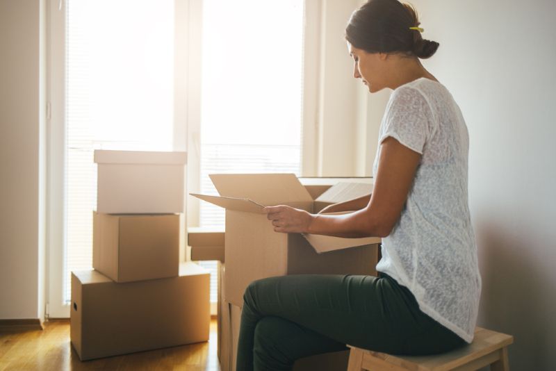Single woman packing up moving boxes in her home