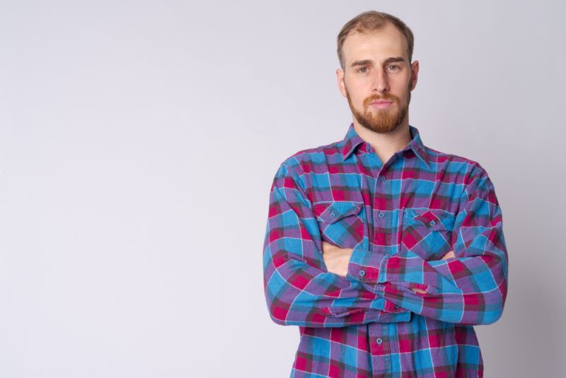Stern man in flannel shirt folding his arms