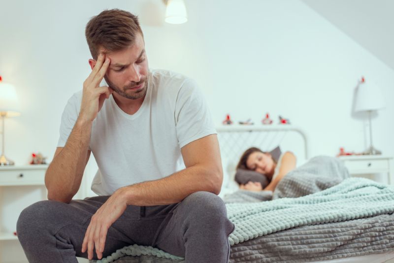 Unhappy couple sitting at opposite ends of the bed