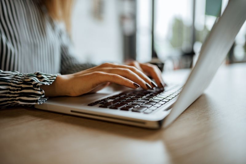 Closeup image of a woman typing on a laptop at home